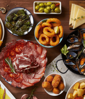 Traditional Andalusian dishes including tapas, gazpacho, seafood, jamón, and paella served on a rustic Spanish table