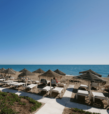 Private beach club with straw umbrellas and sunbeds on Costa del Sol - Andalucia Tours beach day trips from Malaga
