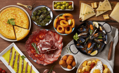 Traditional Andalusian dishes including tapas, gazpacho, seafood, jamón, and paella served on a rustic Spanish table
