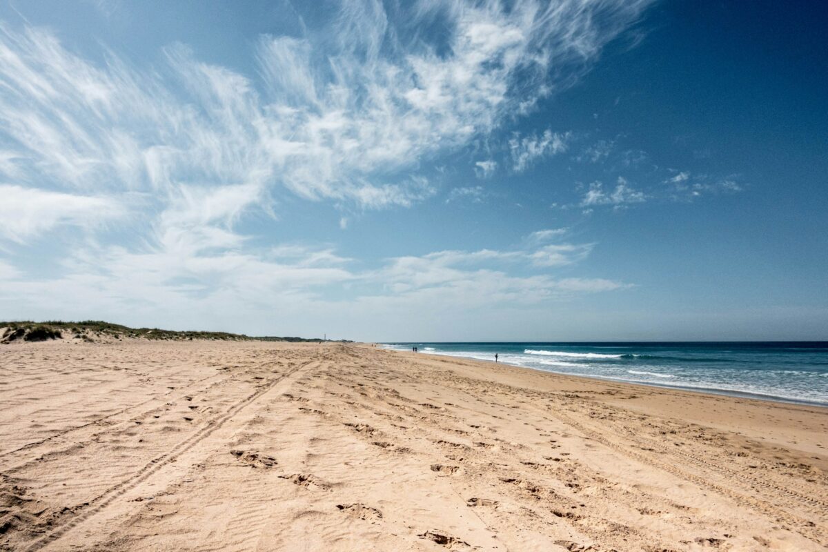 Playa de El Palmar in Cádiz, Andalusia, with golden sand, Atlantic waves, and surfers.